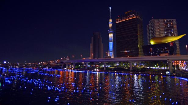 Der Tokyo Skytree und andere Gebäude spiegeln sich nachts im Sumida-Fluss.