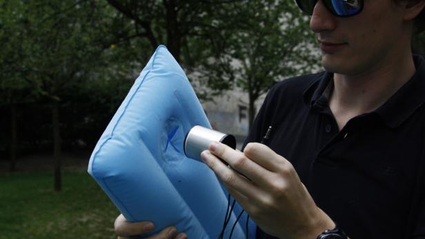 Ein Mann schließt einen Lautsprecher an ein blaues, aufblasbares Kissen an.
