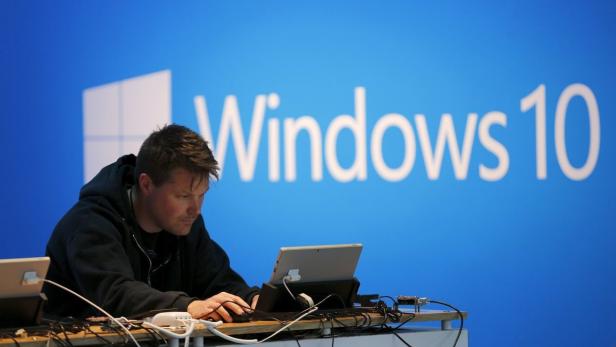 A man works on a laptop computer near a Windows 10