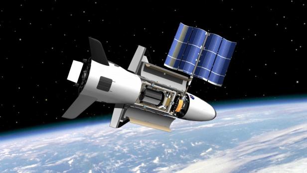 Ein X-37B mit geöffneter Ladebucht und Solarpaneelen über der Erde.