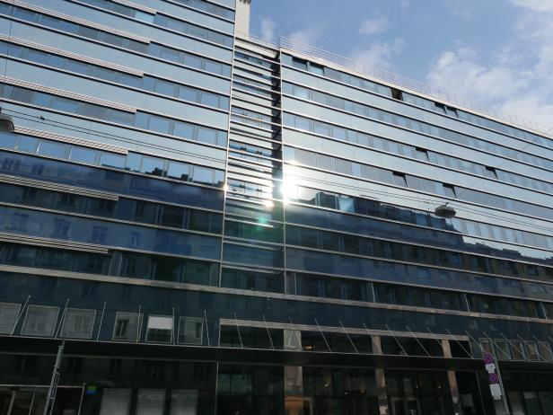 Die Fassade eines modernen Bürogebäudes spiegelt den Himmel wider.