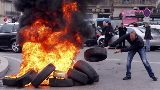 A striking French taxi driver burns tyres during a