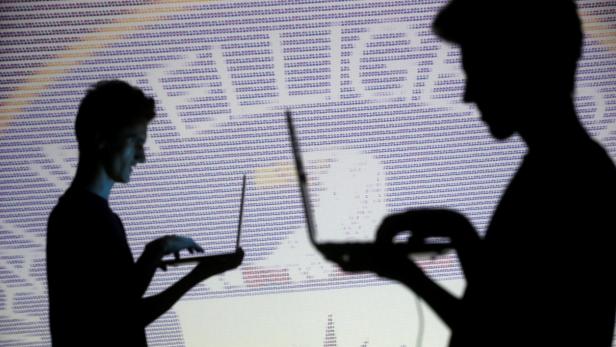FILE PHOTO: People pose with laptops in front of p