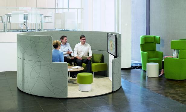 Drei Personen sitzen in einem modernen Besprechungsraum und diskutieren.