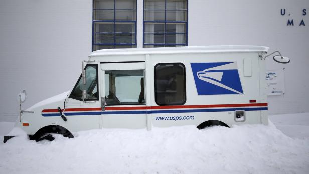A U.S. Postal service delivery truck sits covered