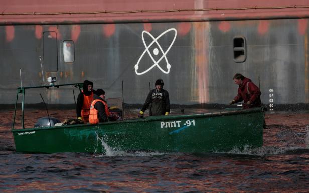 Fishermen sail on a boat past the floating nuclear power plant "Akademik Lomonosov", which is towed to Murmansk for nuclear fuel loading, in St. Petersburg