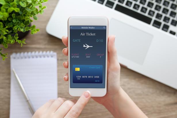 female hand holding phone with online air ticket and notebook