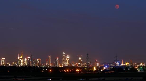 A blood moon is seen in the sky over the skyline of Frankfurt