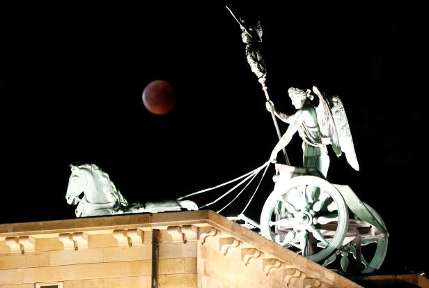 The moon is seen during a lunar eclipse next to the Quadriga atop the Brandenburg Gate in Berlin