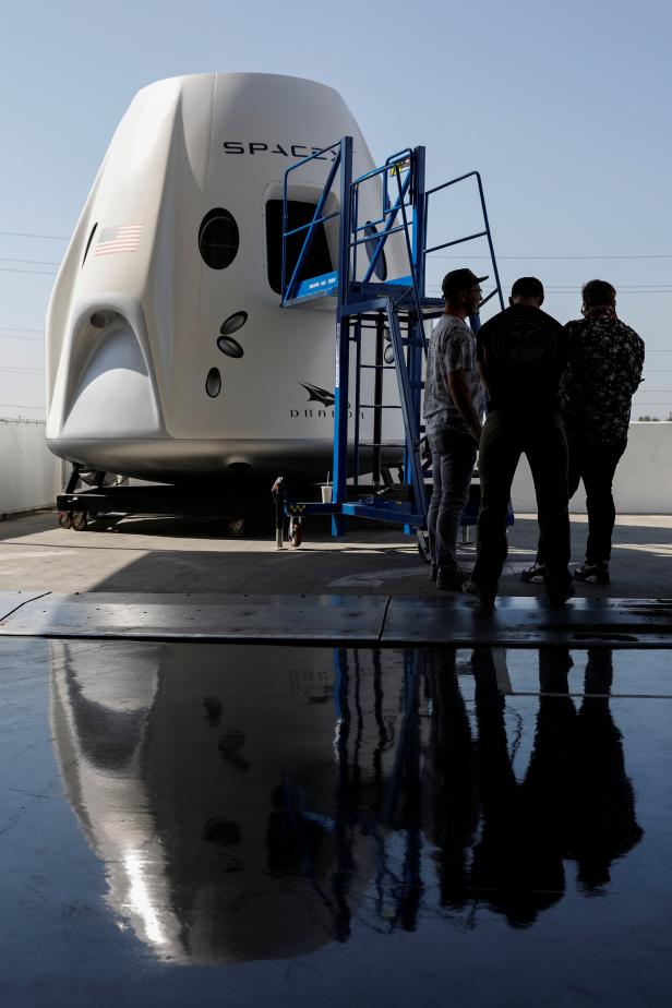 Members of the media gather around a replica of the Crew Dragon spacecraft at SpaceX headquarters in Hawthorne, California