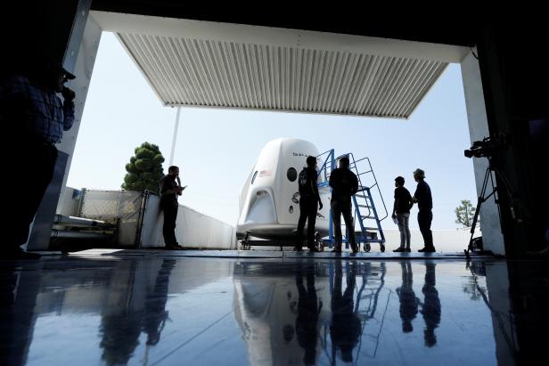 Members of the media gather around a replica of the Crew Dragon spacecraft at SpaceX headquarters in Hawthorne, California