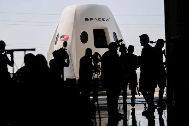 Members of the media gather around a replica of the Crew Dragon spacecraft at SpaceX headquarters in Hawthorne, California