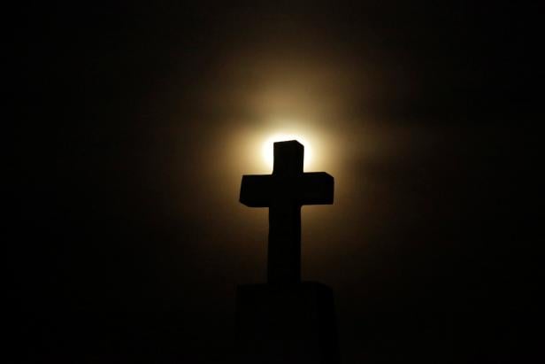 A cross headstone is silhouetted against the full moon ahead of a total lunar eclipse, known as the "super blood wolf moon", at a cemetery in Ciudad Juarez