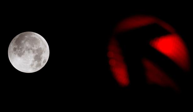 The moon is seen next to a traffic light at the start of a total lunar eclipse in Frankfurt