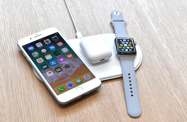 Ein iPhone, eine Apple Watch und AirPods liegen auf einer kabellosen Ladestation.