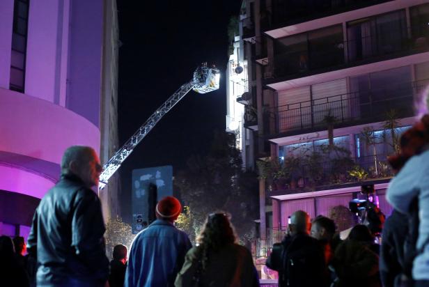 People watch as firefighters work at a building affected by gas poisoning in Santiago