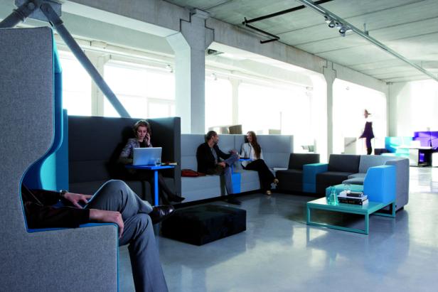 Mehrere Personen sitzen in einem modernen Büro in verschiedenen Sitzbereichen.