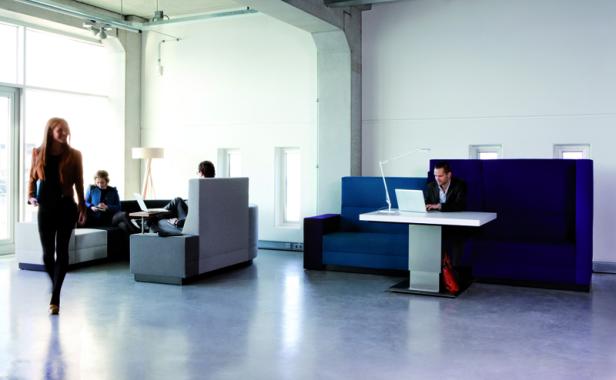 In einem modernen Büro arbeiten mehrere Personen an Laptops und machen Notizen.