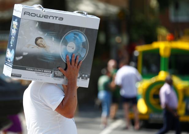 A man carries a ventilator on a hot summer day in Cologne