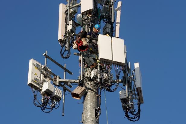 A contract crew from Verizon installs 5G equipment on a tower in Orem