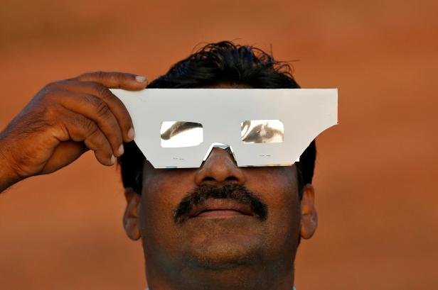 A man uses solar viewers to watch annular solar eclipse in Cheruvathur