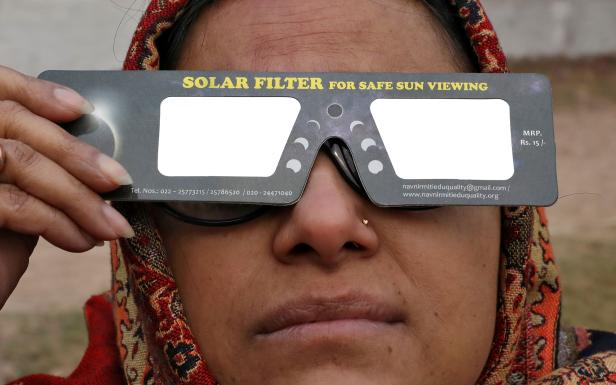 A woman uses solar viewers to watch the solar eclipse in Kolkata