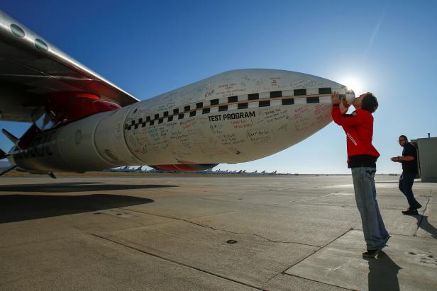 Virgin Orbit's chief engineer Kevin Sagis kisses the tip of a test rocket underneath the wing of a modified Boeing 747 jetliner prior to its takeoff and drop test of its high-altitude launch system for satellites from Mojave, California