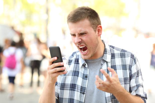 Angry man holding crashed phone