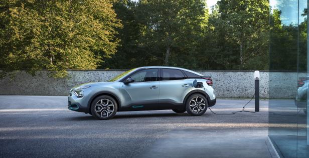 Ein hellblaues Elektroauto wird an einer Ladestation aufgeladen.