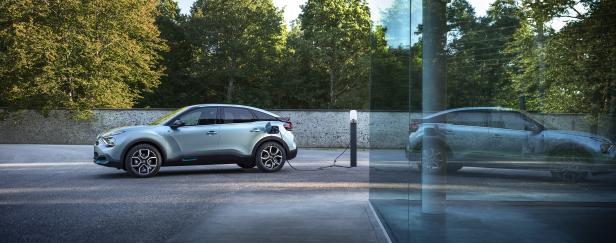 Ein hellblauer Citroën ë-C4 wird an einer Ladestation aufgeladen.