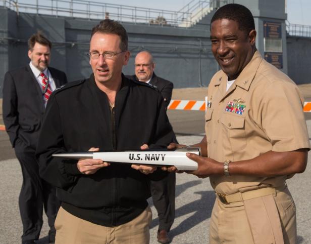 Zwei US Navy-Offiziere halten ein Objekt mit der Aufschrift „U.S. Navy“.