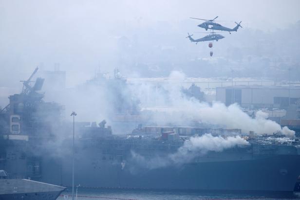 U.S. Navy helicopters and city firefighters continue fighting a fire on the amphibious assault ship USS Bonhomme Richard at Naval Base San Diego