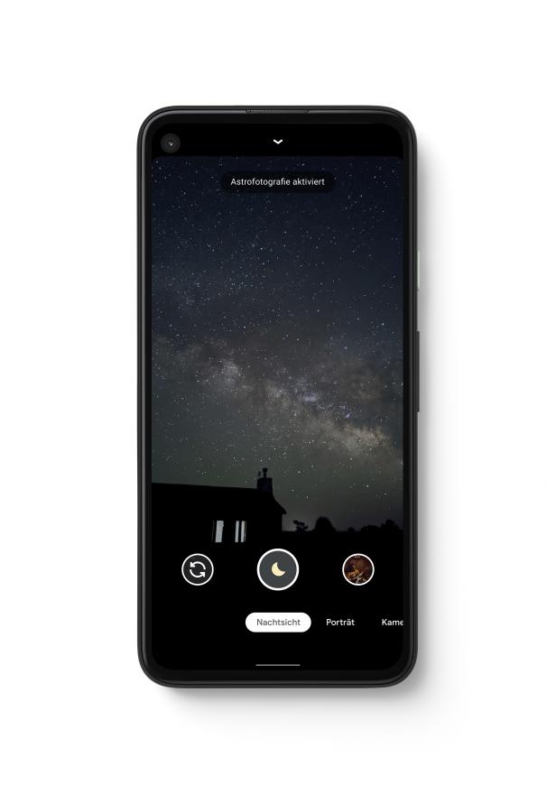 Ein Smartphone zeigt im Nachtsichtmodus den Sternenhimmel über einem Haus.