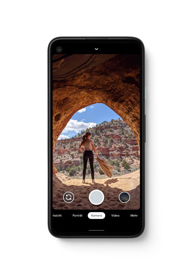 Eine Frau steht in einer Felsenhöhle und blickt auf die Landschaft.