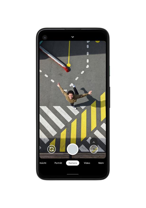 Ein Mann steht auf einer farbenfrohen Straßenmarkierung und streckt die Arme aus.