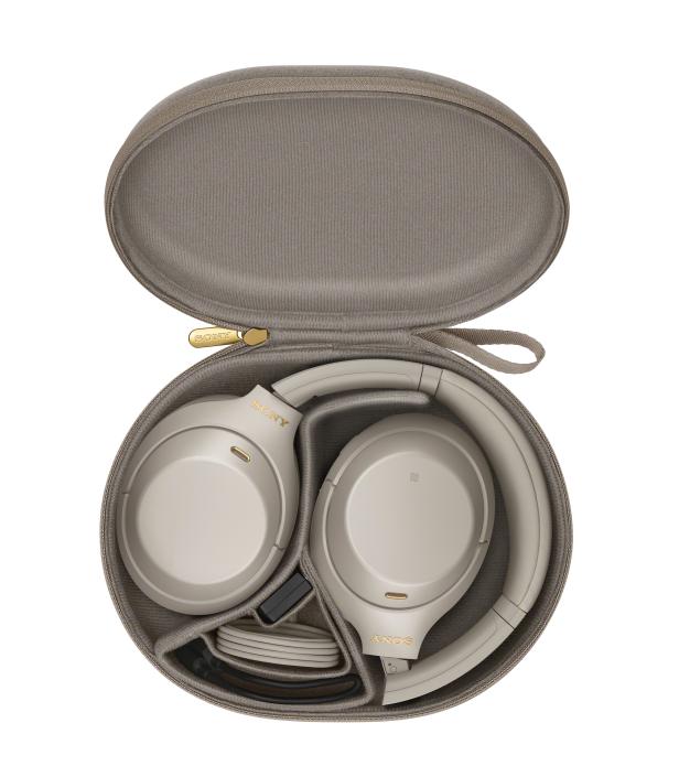 Ein Paar beige Sony-Kopfhörer liegen in einem geöffneten, runden Etui.