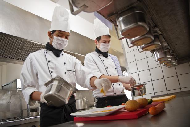 Chef and trainee work in a hotel kitchen, preparing a meal