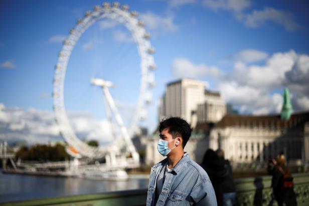 A man wearing a protective face mask walks across Westminster bridge, during the coronavirus disease (COVID-19) outbreak, in London