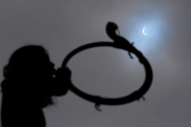 A Mapuche Indian child blows a 'Trutruca', a musical instrument, during a solar eclipse at Freire area, Temuco