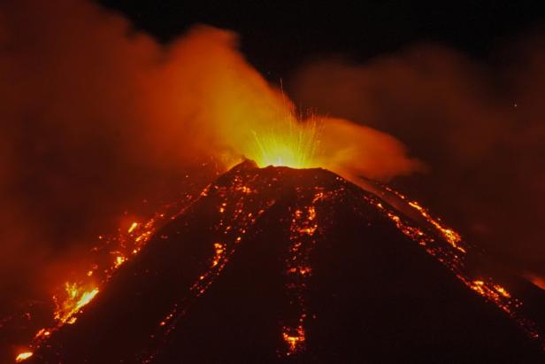 An eruption from Mount Etna lights up the sky during the night, seen from Fornazzo