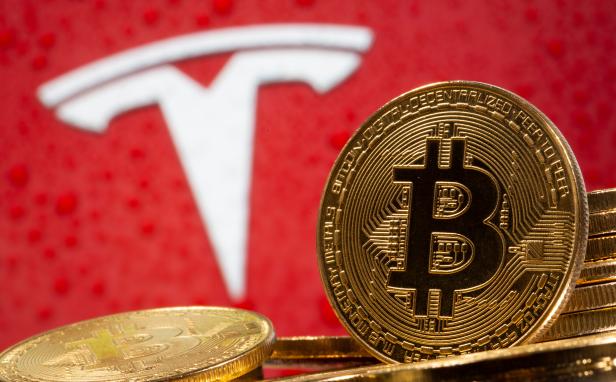 Representations of virtual currency Bitcoin are seen in front of Tesla logo in this illustration