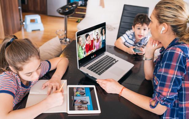 Mother talk with friends on laptop while watching two kids staying home Homeschooling and distance learning