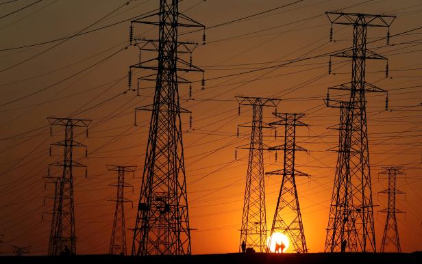 FILE PHOTO: Locals walk past Eskom's electricity pylons as they return from work in Orlando