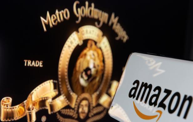 Smartphone with Amazon logo is seen in front of displayed MGM logo in this illustration taken