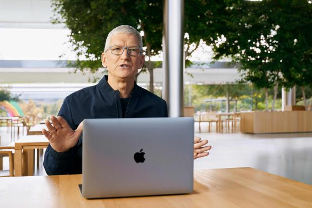 Tim Cook mit MacBook in leerem Saal des Apple Park 