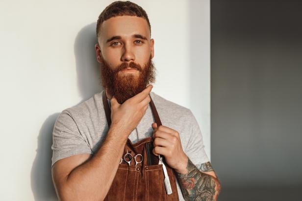 Male stylist stroking beard and looking at camera
