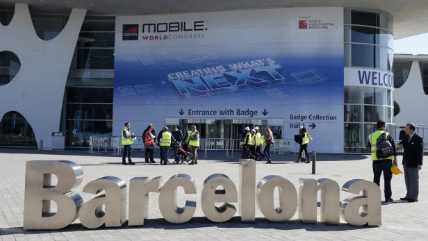 Workers walk past a Mobile World Congress entrance