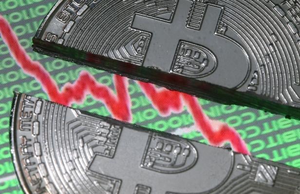 FILE PHOTO: Broken representation of the Bitcoin virtual currency, placed on a monitor that displays stock graph and binary codes, are seen in this illustration picture