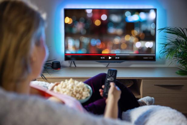 Woman relaxing at home in evening and watching TV