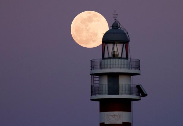 Full moon known as the "Flower Moon" rises behind the Arinaga lighthouse